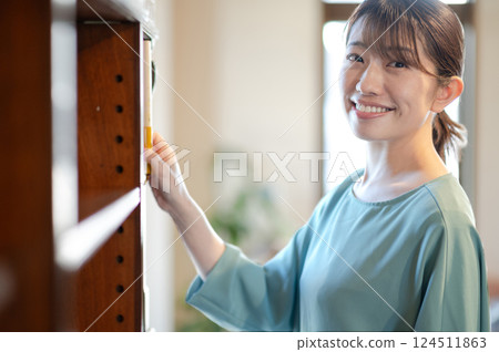 一位女士從書架上拿起一本書 124511863