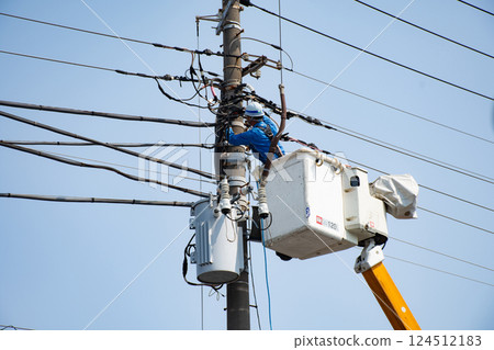 A worker doing electrical work at a high place on a utility pole 124512183