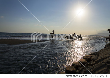 Unrecognizable people riding horses on the beach at dawn, Crete, Greece Unrecognizable people riding horses on the beach at dawn, Crete, Greece 124512891