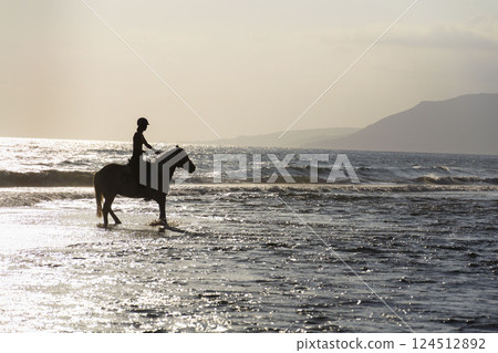 Unrecognizable people riding horses on the beach at dawn, Crete, Greece Unrecognizable people riding horses on the beach at dawn, Crete, Greece 124512892