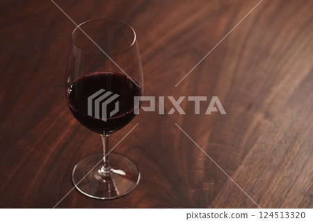 Red wine in thin wine glass on wood table Red wine in thin wine glass on wood table 124513320