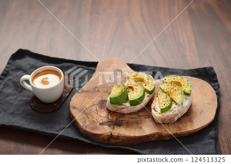 Avocado sandwiches with espresso for breakfast on walnut wood table 124513325