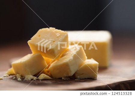 White cheddar cheese pieces on olive wood board 124513328