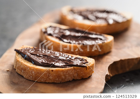 Rustic ciabatta with organic chocolate cream on olive wood board 124513329