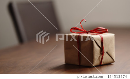 Slide tracking shot of brown paper gift box with red bow on wood table with blank paper card 124513374