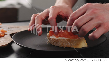 man hands making bruschetta with cream cheese and salted trout on black plate 124513380