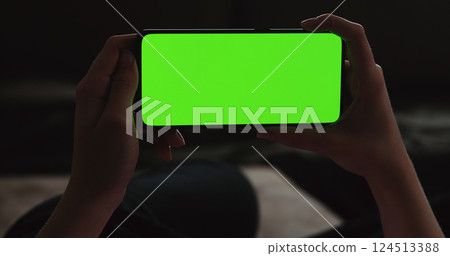 Young woman lying on a couch and using smartphone with horizontal green screen Young woman lying on a couch and using smartphone with horizontal green screen 124513388