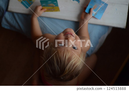 Child Joyfully Playing with Cards on Table from Above 124513888