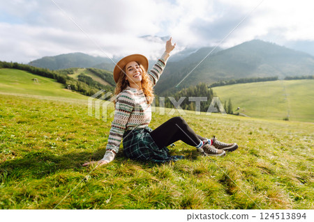 Cute traveler in hat takes selfie against backdrop of green mountain landscapes. Concept of freedom 124513894