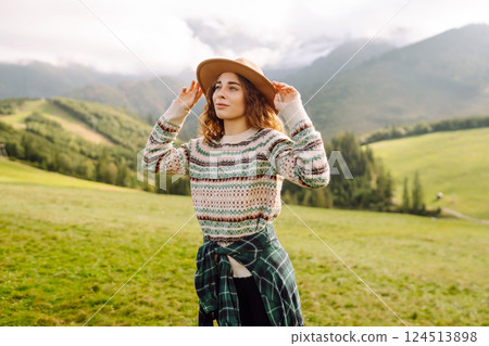 Cute traveler in hat takes selfie against backdrop of green mountain landscapes. Concept of freedom Cute traveler in hat takes selfie against backdrop of green mountain landscapes. Concept of freedom 124513898