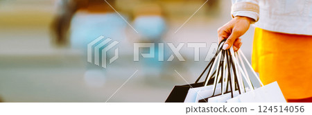 Young woman with shopping bags walking on street. Female coming from a sale downtown 124514056