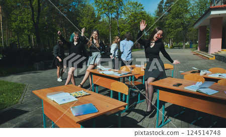 High school students happily dancing and enjoying themselves in the schoolyard on a sunny day 124514748