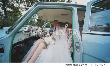 Bride and groom sharing an intimate moment inside a classic car, celebrating their wedding day with romance and style 124514749