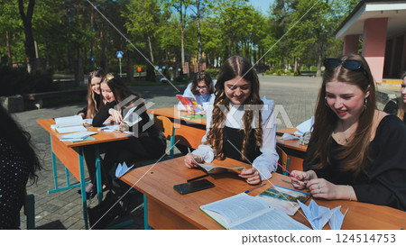 High school girls studying and learning together at outdoor desks on a sunny school day 124514753