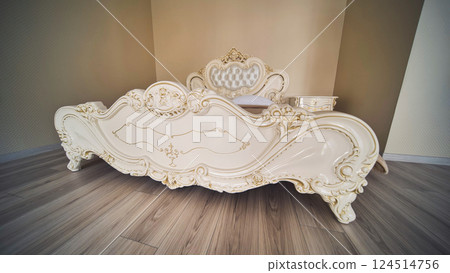 Elegant king size bed with gold decorations in a luxurious bedroom, ideal for a wedding day or honeymoon 124514756