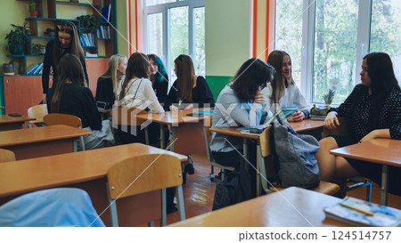Classroom socialization, teenagers and their teacher engaging in conversations and bonding during break time 124514757