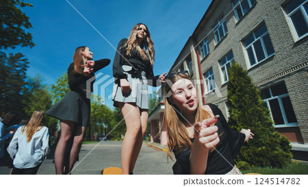 Three cheerful high school girls pointing and enjoying their time together on a sunny school day, celebrating friendship and education Three cheerful high school girls pointing and enjoying their time together on a sunny school day, celebrating friendship and education 124514782