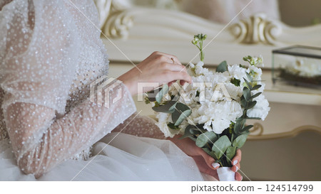 Bride in white dress holding white bouquet with eucalyptus leaves and wearing golden ring on her finger Bride in white dress holding white bouquet with eucalyptus leaves and wearing golden ring on her finger 124514799