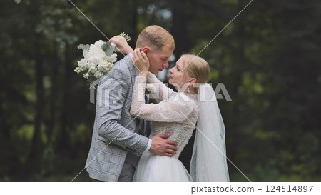 Loving newlyweds hugging amid woodland trees, sharing intimate moment during marriage celebration 124514897