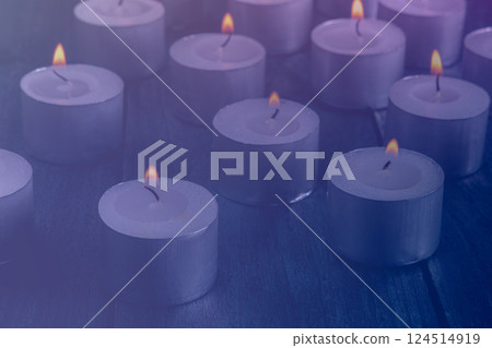Tea light candles on a dark background, many lights in the dark Tea light candles on a dark background, many lights in the dark 124514919