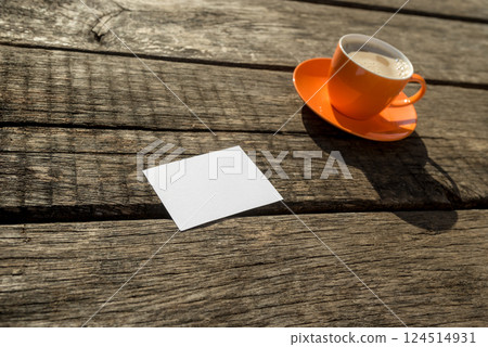 Blank paper next to orange cup of coffee 124514931