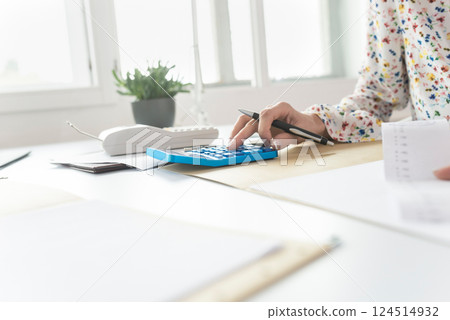 Businesswoman doing a calculation on a manual desktop calculator 124514932