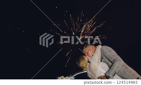 Romantic couple kissing under exploding fireworks during night wedding celebration, creating magical and unforgettable moment Romantic couple kissing under exploding fireworks during night wedding celebration, creating magical and unforgettable moment 124514965