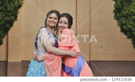 Graduates wearing formal attire embracing, celebrating academic success and close bond between friends Graduates wearing formal attire embracing, celebrating academic success and close bond between friends 124515036