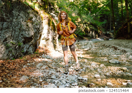 Traveler woman walking along hiking trail through forest thicket in the mountains. Active lifestyle. 124515464