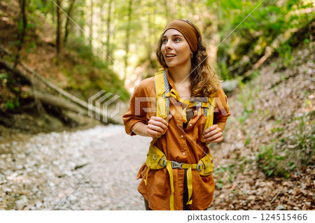 Traveler woman walking along hiking trail through forest thicket in the mountains. Active lifestyle. Traveler woman walking along hiking trail through forest thicket in the mountains. Active lifestyle. 124515466