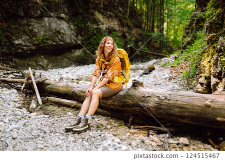 Traveler woman walking along hiking trail through forest thicket in the mountains. Active lifestyle. Traveler woman walking along hiking trail through forest thicket in the mountains. Active lifestyle. 124515467