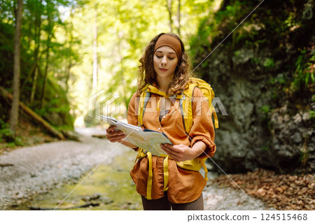 Young woman on a mountain path with a map in her hands, exploring hiking trails. Adventure concept. 124515468