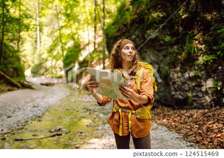 Young woman on a mountain path with a map in her hands, exploring hiking trails. Adventure concept. 124515469