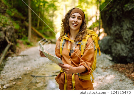 Young woman on a mountain path with a map in her hands, exploring hiking trails. Adventure concept. Young woman on a mountain path with a map in her hands, exploring hiking trails. Adventure concept. 124515470