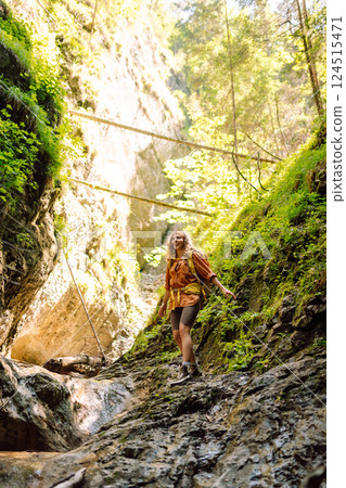 Woman traveler with a hiking yellow backpack explores new places, collects water from a stream Woman traveler with a hiking yellow backpack explores new places, collects water from a stream 124515471