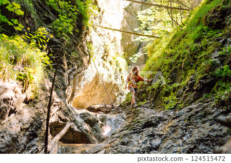 Woman traveler with a hiking yellow backpack explores new places, collects water from a stream Woman traveler with a hiking yellow backpack explores new places, collects water from a stream 124515472