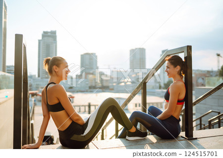 Two women in sportive clothes have fitness day outdoors together. Active life, healthy lifestyle. Two women in sportive clothes have fitness day outdoors together. Active life, healthy lifestyle. 124515701