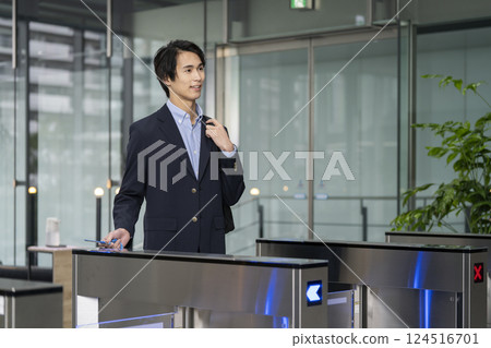 年輕商人穿過辦公大樓的安全門 年輕商人穿過辦公大樓的安全門 124516701