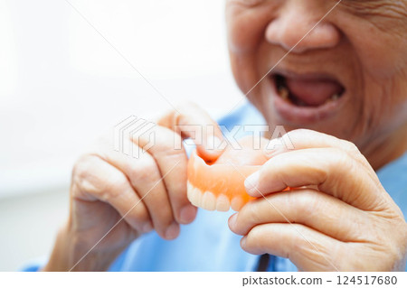 Asian senior woman patient wearing teeth denture into her mouth for chew food. Asian senior woman patient wearing teeth denture into her mouth for chew food. 124517680