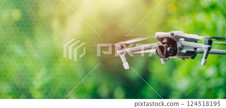 Drone UAV unmanned aerial vehicle with camera, Dron fly on blur green background wide for banner. 124518195