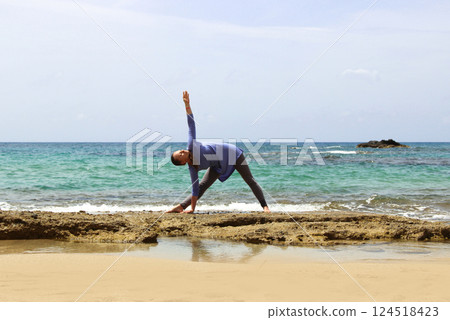 young woman doing yoga exercise on the beach 124518423