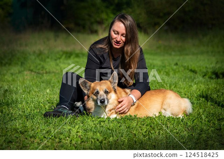 Girl playing with corgi on the lawn on a sunny summer day 124518425
