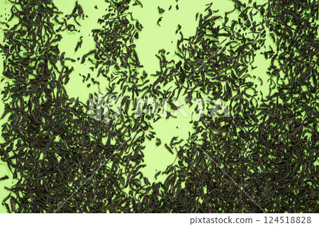 Loose black tea scattered on green background 124518828