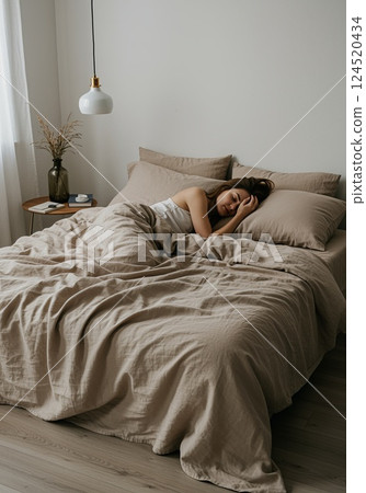 Woman sleeping in luxurious bed linens with an airy atmosphere 124520434