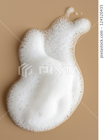 Fluffy white foam in droplet shape on light brown background with soft texture 124520435