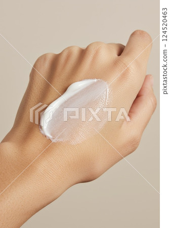 Close-up of hand with white cream smear against neutral background 124520463