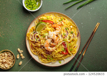 Pad thai noodles with shrimp, peanuts and lime on green background, dish of Thailand 124520633