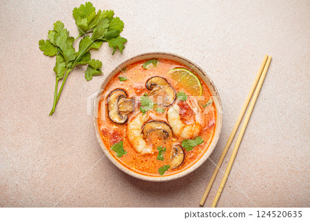 Tom yum soup with shrimp and mushrooms in bowl with chopsticks top view, traditional Thai soup 124520635