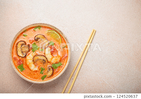 Tom yum soup with shrimp and mushrooms in bowl with chopsticks top view, traditional Thai soup, space for text 124520637