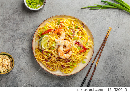 Pad thai noodles with shrimp, peanuts and lime on grey background, dish of Thailand Pad thai noodles with shrimp, peanuts and lime on grey background, dish of Thailand 124520643